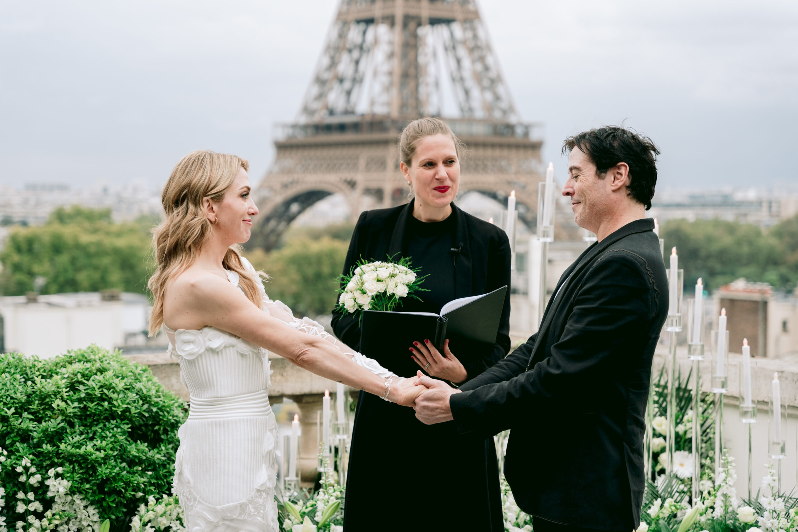 Bride and groom holding hands during their wedding ceremony with the Eiffel Tower in the backgrond. Captured by Fioroni Photography